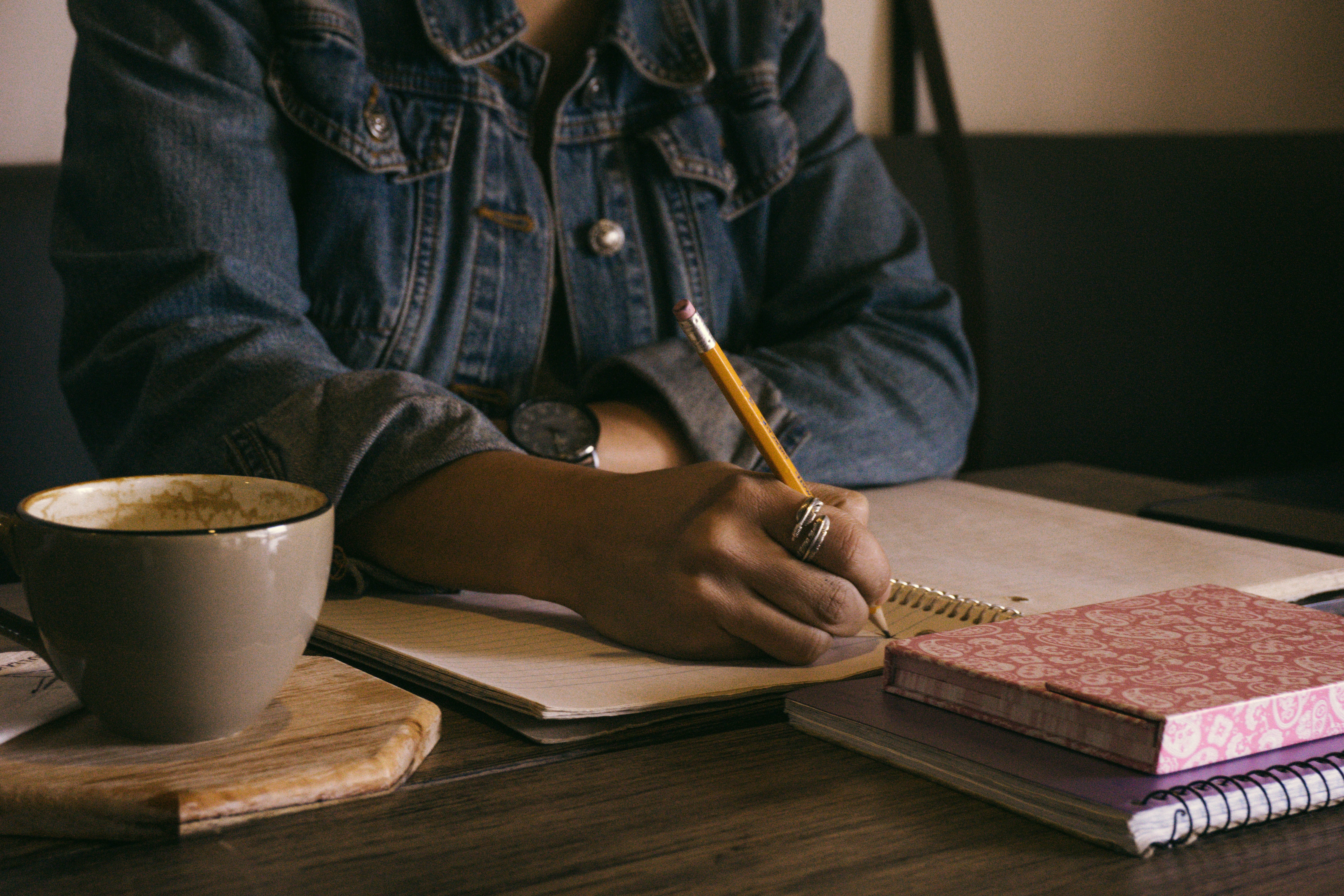 Photo of someone writing, by Kat Stokes on Unsplash